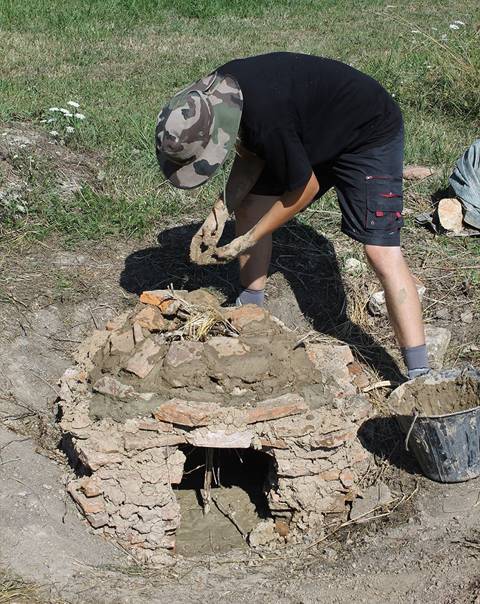 Bénévole de la Société de Recherches Archéologique de l'Alsace Bossue en pleine confection du four à pain antique