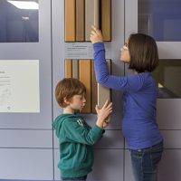 Deux enfants qui découvrent des ressources pédagogiques dans la salle bleue de l'exposition du CIP La Villa, musée d'archéologie à Dehlingen